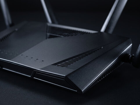Black Wireless Network Router With Antennas Positioned On Dark Desk