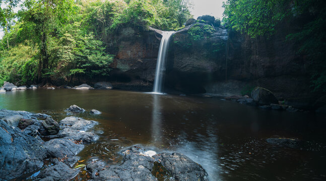 Serene Waterfall in Yai Surrounded by Lush Greenery and Rocks