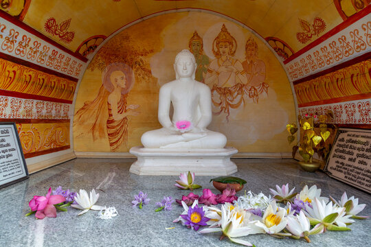 White seated Buddha statue with lotus flower offerings inside a painted shrine at Ruwanwelisaya, North Central Province, Anuradhapura, Sri Lanka