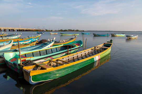 Colorful wooden fishing boats moored in calm water near a long bridge, Northern Province, Mannar, Sri Lanka