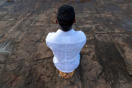 Man in a white shirt kneeling barefoot on a stone surface at Ruwanwelisaya, North Central Province, Anuradhapura, Sri Lanka