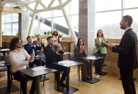 Team audience applauds speaker coach during business training. Professionals in an office classroom cheer the manager after seminar. Concept shows leadership, teamwork, success and applause.