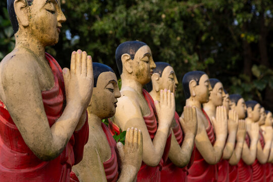 Row of praying monk statues with joined hands at Sigiriya Buddhist Temple, Central Province, Sigiriya, Sri Lanka