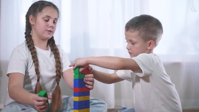 Two children playing with lifestyle blocks. A group of children are assembling a construction. A group of kids play with toys. Two kids stacking blocks.