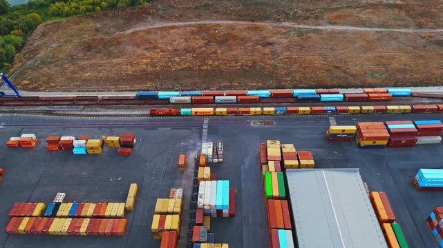 Sremska Mitrovica, Serbia - 01 October 2026: Aerial view of a freight train and colorful shipping containers in a logistics yard.