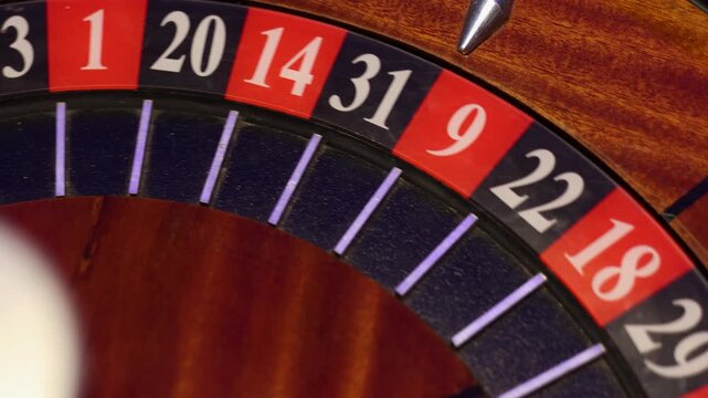 Vintage wooden roulette wheel spinning with ball landing on number 7. Authentic casino gambling equipment in close up view with classic gaming table details.