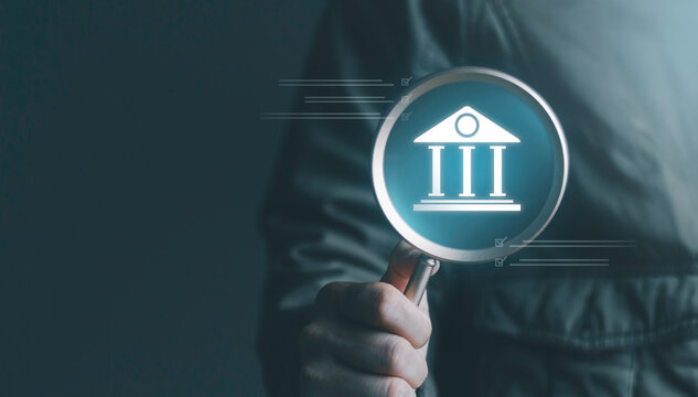 Banking compliance, financial inspection, and regulatory review. Financial audit concept showing a magnifying glass highlighting a bank building icon with digital checklist graphics.