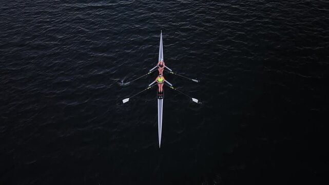 High-altitude drone view of an early morning rowing practice in Halifax Harbour, showing women and men training in single sculls and double sculls across the coastal bay