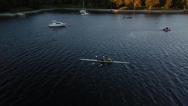 Drone view of an early morning rowing session in Halifax, Nova Scotia, Canada, with women and men training in single and double racing shells across the open harbour.