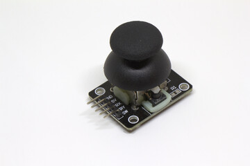Analog thumb joystick module with black cap and pin header on white background, top angle view © Engin