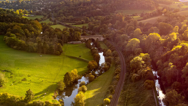 Golden hour sunlight illuminates the rural valley bridge and river.