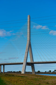 View of the Flintshire Bridge, a cable-stayed bridge with a tall concrete pylon and steel cables spanning over the river under a clear blue sky in Deeside, Wales, United Kingdom.