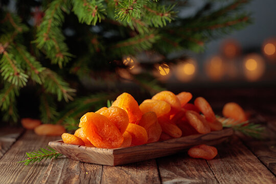 Dried apricots in wooden dish and fir tree branches.