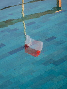 View of the reflection of a red and white object in the clear blue water of a tiled swimming pool in Lamboya, East Nusa Tenggara, Indonesia.