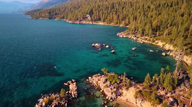 Wooded slopes curve around the turquoise coves of Lake Tahoe. An elevated view shows scattered boulders and pale beaches beneath mountains in the distance.