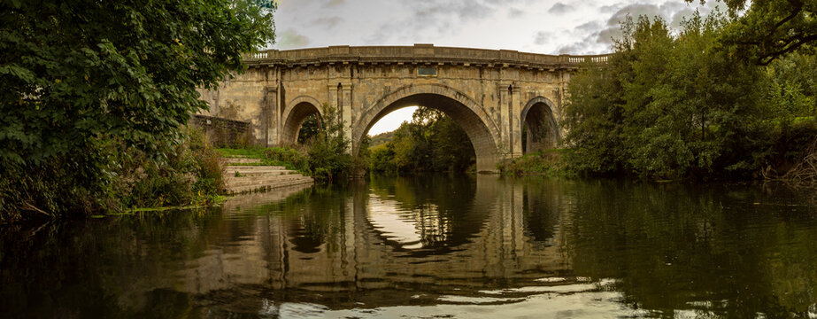 Dundas Aqueduct reflects on the calm canal at sunset in Bath.