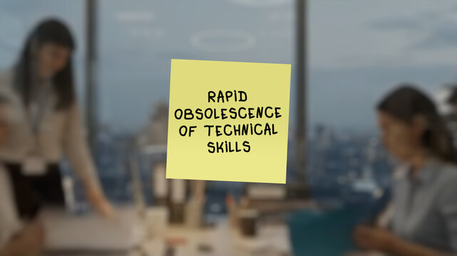 Adhesive note with the text "rapid obsolescence of technical skills" in the foreground area, superimposed on a blurred background showing an shared workspace.