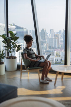 A freelancer works in a lounge overlooking a vast cityscape.