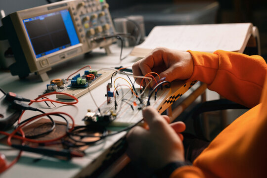 Hands Building Electronic Circuit on Breadboard in Workshop
