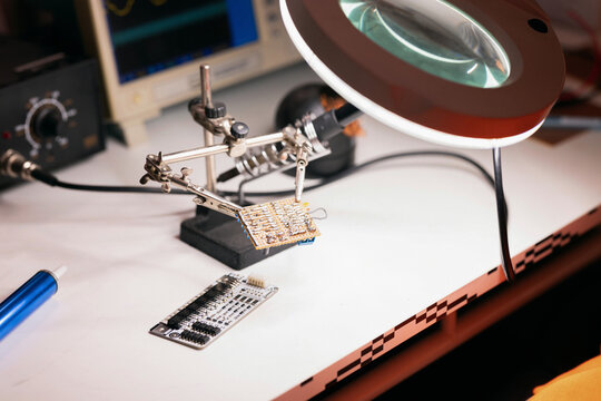 Electronics Soldering Workspace With Circuit Boards And Magnifier
