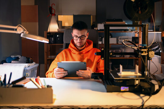 Designer Using Tablet Near 3D Printer In Workshop