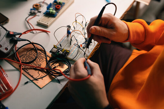 Hands Testing Electronics On Breadboard With Multimeter Probes