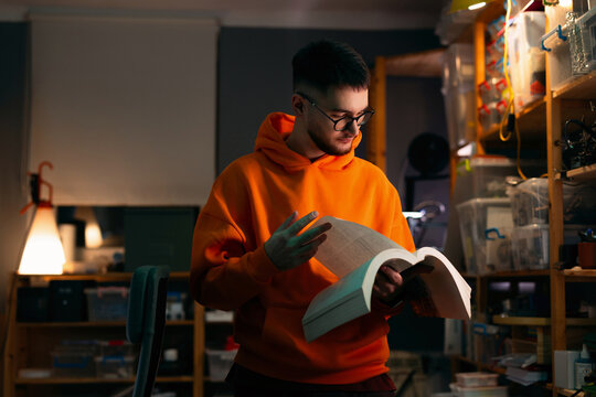 Young Man Reading Technical Book in Workshop