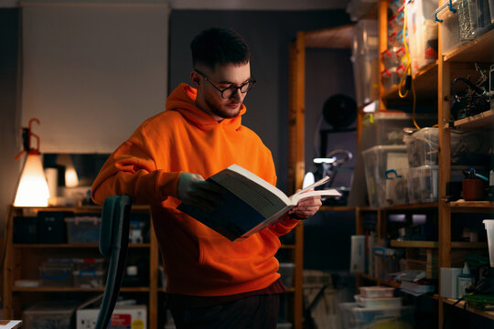 Young Man Reading a Book in Electronics Workshop