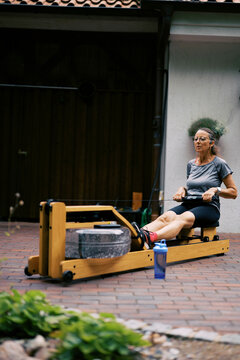 middle aged women working out outdoors with rowing fitness machine
