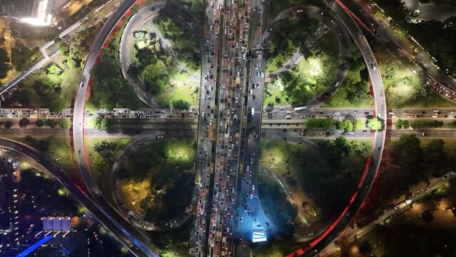 Aerial view of Semanggi interchange at night with heavy traffic flowing through the illuminated cloverleaf roads in Jakarta Selatan, DKI Jakarta, Indonesia.