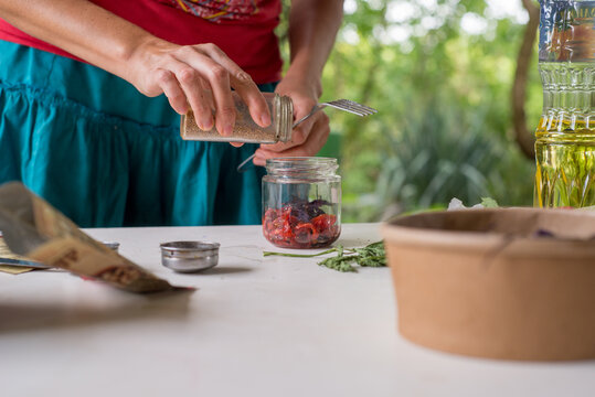 Faceless woman is preserving sun-dried tomatoes for the winter.