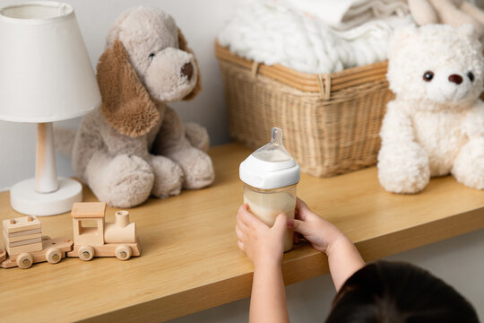 Cropped hands of a toddler reaching for a baby feeding bottle