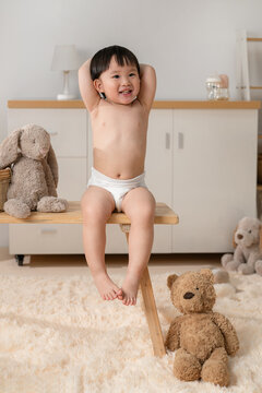 Happy Toddler in Diaper sits on a wooden stool