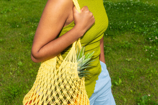 Shopper carrying reusable fruit bag outdoors
