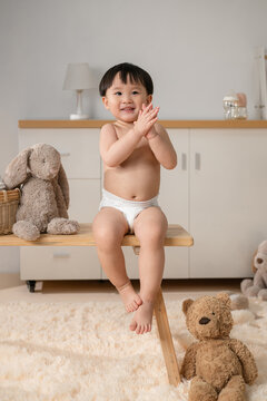 Happy Baby Clapping Hands sits on a wooden bench