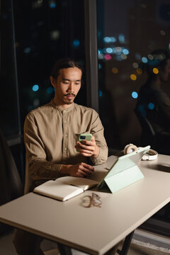 Man Using Smartphone and Tablet in Modern Workspace