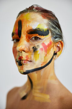 Person with colorful face paint posing indoors