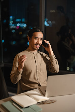 Man Talking on Phone While Working at Desk at Night