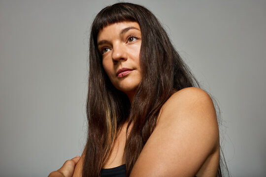 Woman with long hair poses against a plain background