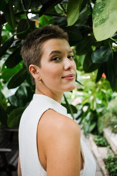 Woman Standing Among Green Leaves in a Garden Setting