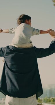 Shoulder, ride and dad with child, holding hands and spinning with son on weekend or dance together. Happy family, man and play with kid on break, love and connection with father on rooftop at home