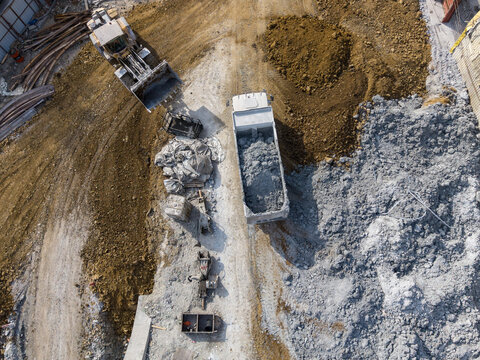 Aerial view of a construction site featuring a bulldozer and a dump truck loaded with gravel, surrounded by piles of dirt and rocky ground in Istanbul, Istanbul, Turkiye.