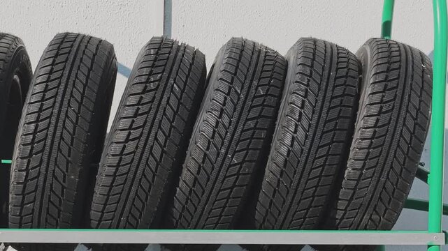 Rows of new winter tires for sale displayed on a rack at an auto repair shop. Vehicle maintenance and seasonal tire change concept