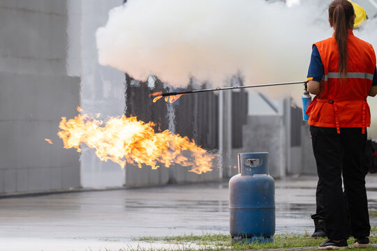 Employees firefighting training in the factory.Employees using fire extinguisher fighting fire.Closeup. spray fire extinguisher to cooking gas cylinder.
