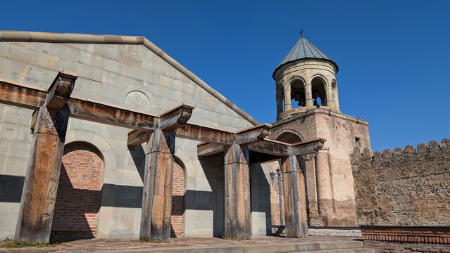 Low angle view of an ancient orthodox stone church with a bell tower and wooden structures in Mtskheta, Georgia
