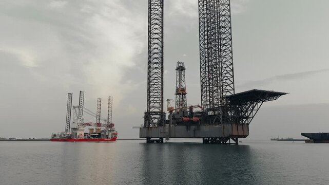 Side view of a jack up drilling platform in an industrial harbor
