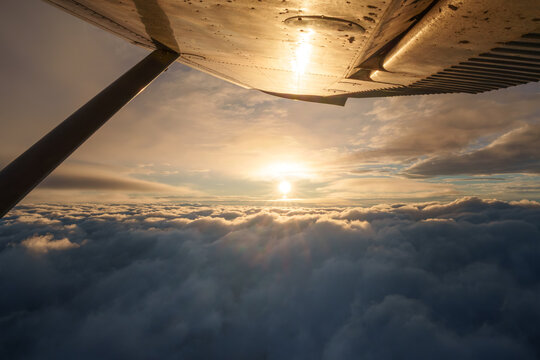 Aerial view of a golden sunset over a thick layer of clouds seen from an airplane wing in Salt Lake City, Utah, United States.