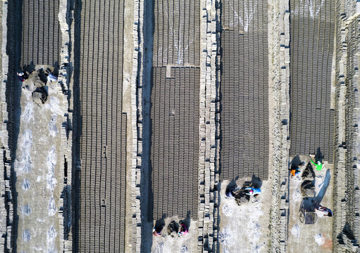 Aerial view of workers arranging rows of drying mud bricks in a brickyard in Gaibandha Sadar Upazila, Rangpur Division, Bangladesh.