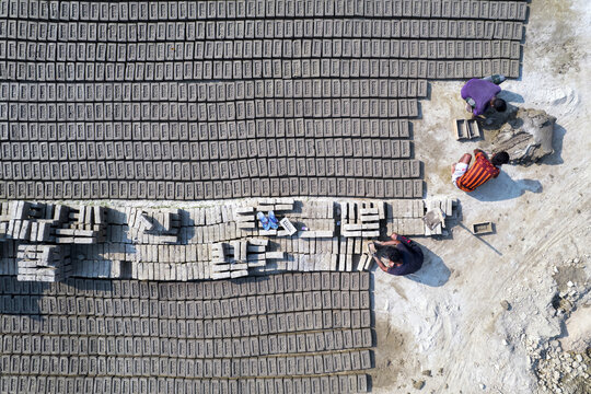Aerial view of workers arranging rows of handmade clay bricks in a brick field in Gaibandha Sadar Upazila, Rangpur Division, Bangladesh.