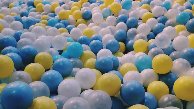 Colorful ball pit with blue yellow white balls moving - kids playground background 4K
